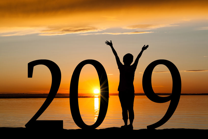 2019 new year silhouette of a girl with hands raised at the beach during golden sunrise or sunset with copy space. concept of joy, praise, worship, connection with nature.