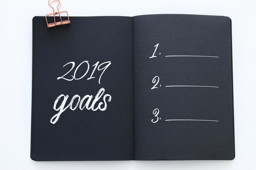 Top view 2019 goals list with notebook over wooden white desk